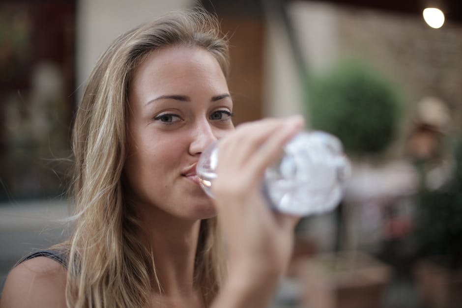 A person drinking water in the morning with a smile on their face.