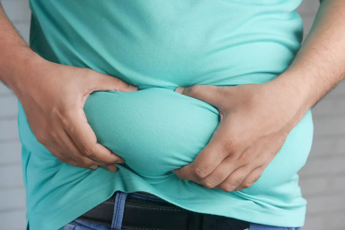 A person holding their stomach, expressing discomfort due to bloating.