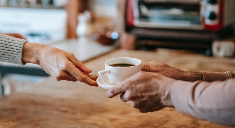 Image depicting a person drinking coffee and water, representing the relationship between caffeine and hydration.