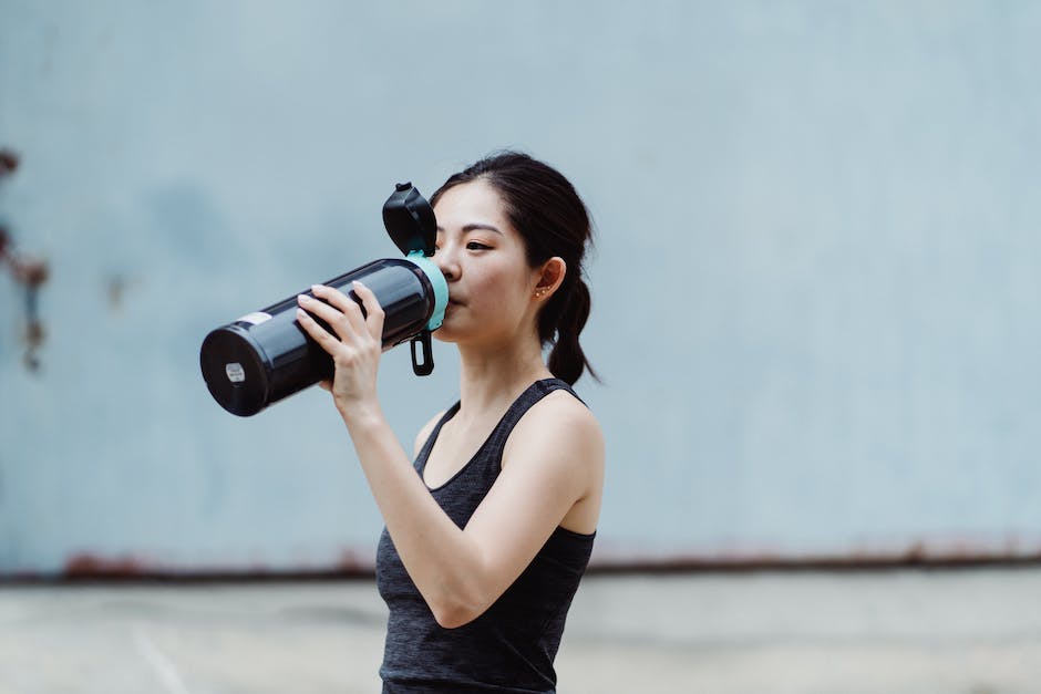 A woman drinking water from a bottle during exercise