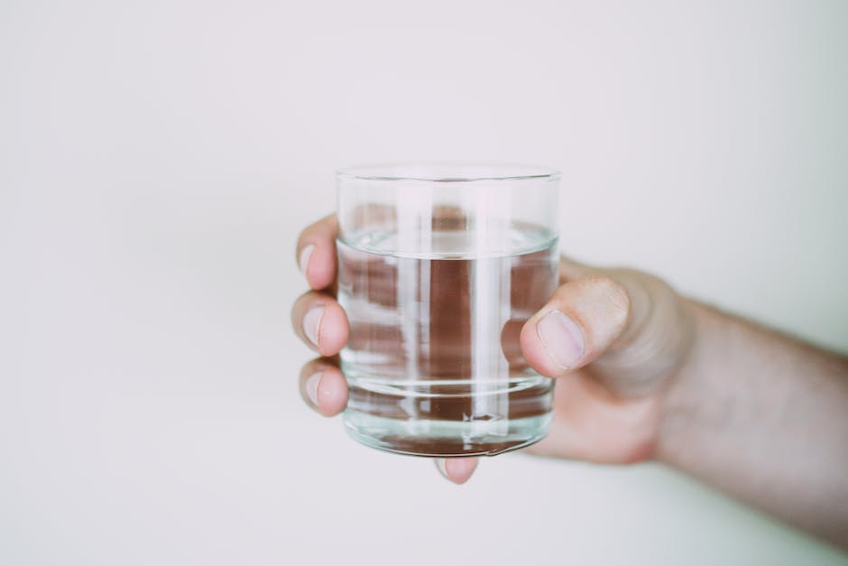 Image of a person drinking water from a glass, symbolizing hydration goals with water trackers