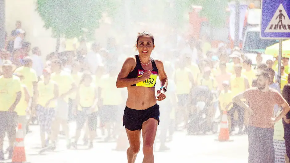 A person running a marathon and drinking water from a bottle.