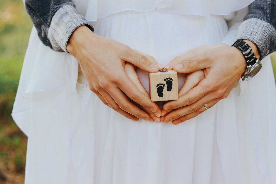 A couple holding hands with a pregnant woman's belly in the foreground, representing the concept of sympathetic pregnancy.